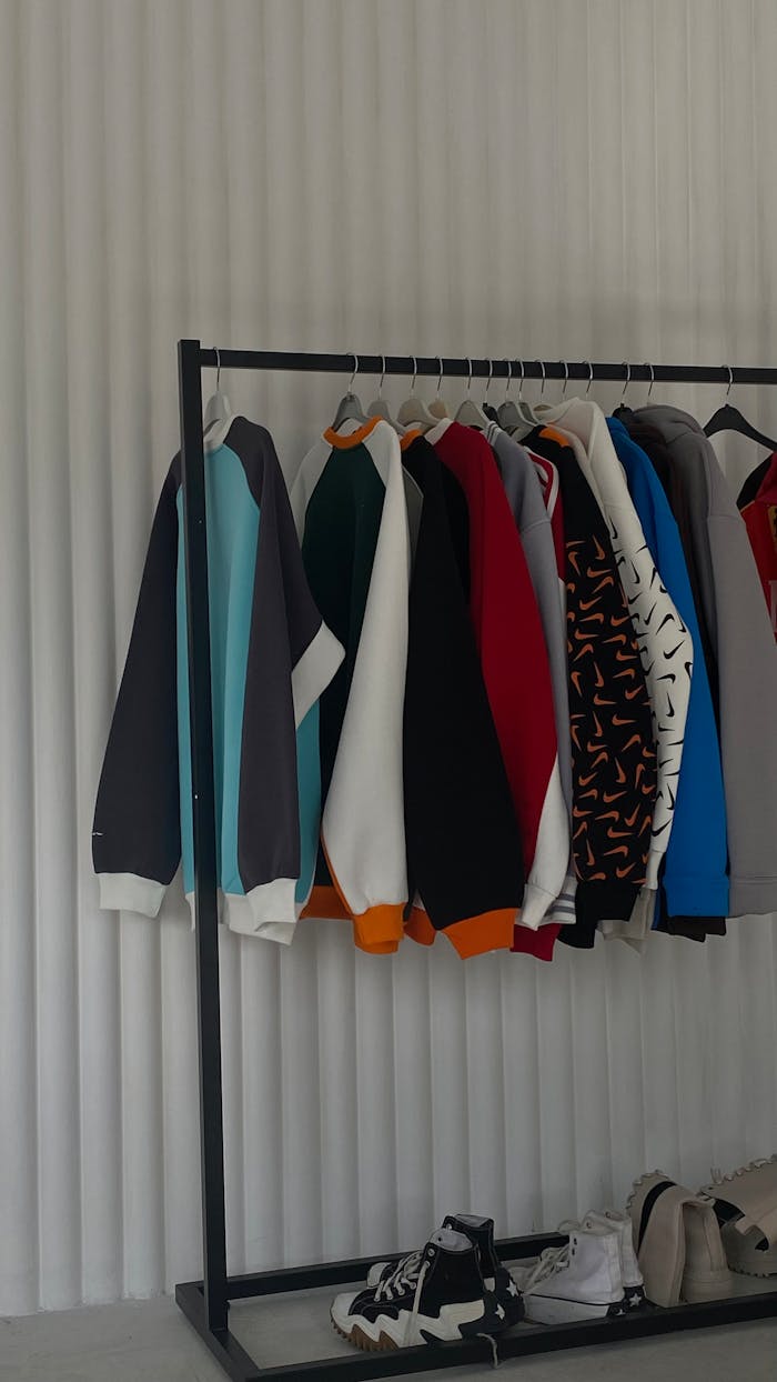 Minimalist rack displaying colorful sweatshirts against white backdrop in a trendy setting.